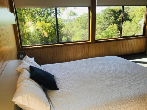 a bedroom with a bed with two pillows and two windows at Metung Getaway in Metung