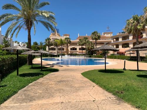 un complejo con piscina, palmeras y sombrillas en CASA BAIANA - Dúplex en Costa Ballena, en Costa Ballena