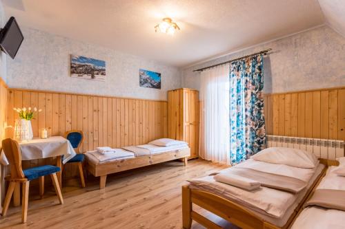 Una habitación con dos camas y una mesa dentro. en Gościniec Nad Potokiem, en Małe Ciche