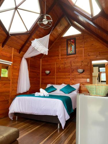 1 dormitorio con 1 cama en una habitación con paredes de madera en GLAMPING VILLA PALVA en VILLA DE LEYVA en Villa de Leyva