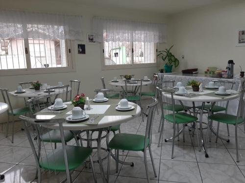 uma sala de jantar com mesas e cadeiras verdes em Pousada São Francisco em Bento Gonçalves