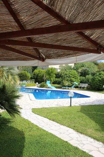a swimming pool in a yard with a wooden roof at B&B Le Vele in Maruggio