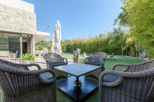 a patio with three wicker chairs and a table at SERRENDY Villa in Juan-Les-pins heated pool in Antibes
