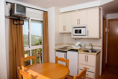 a small kitchen with a table and a microwave at Alojamientos Madrigal in Cazorla