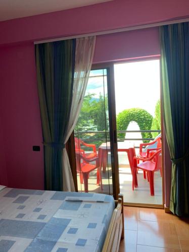 a bedroom with a bed and a balcony with chairs at Vila Deni in Tushemisht