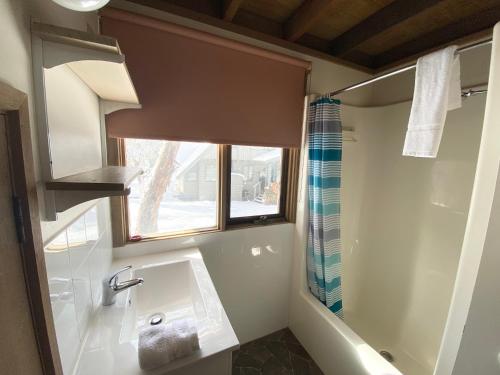 uma casa de banho com um lavatório, uma janela e uma banheira em Jagungal em Dinner Plain