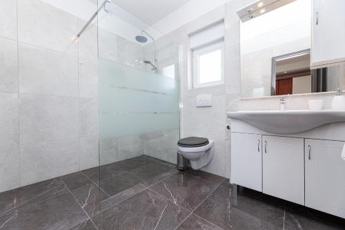 biała łazienka z umywalką i toaletą w obiekcie Villa Mia w mieście Garica
