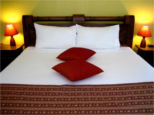 a large bed with two red pillows on it at Coconut Palms On The Bay in Hervey Bay