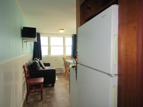 a kitchen with a refrigerator and a living room at Oceana Cottages in North Truro