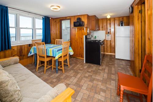a kitchen and living room with a table and a refrigerator at Oceana Cottages in North Truro
