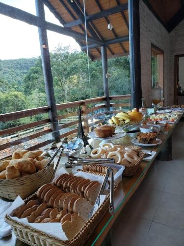 une longue table avec du pain et des paniers de nourriture dessus dans l'établissement Pousada Cabana na Floresta - Monte Verde, à Camanducaia