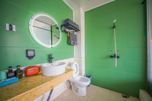 a green bathroom with a sink and a toilet at Lijiang Guchengyuan INN in Lijiang