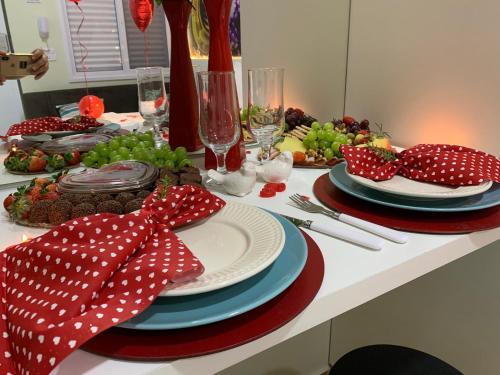 a table with red and white plates and fruit on it at Suite Starfish in Guarujá
