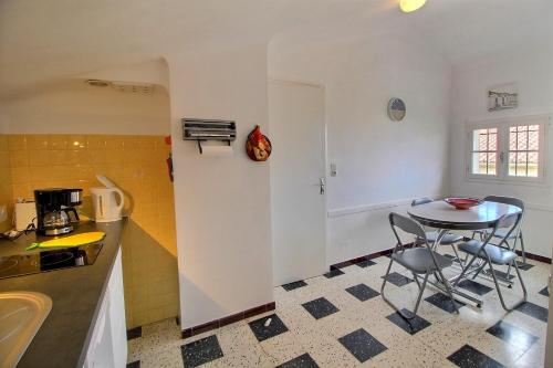 une cuisine avec une table et des chaises dans une pièce dans l'établissement Meublé trois étoiles au premier étage d’une maison typique, à Saint-Cyprien