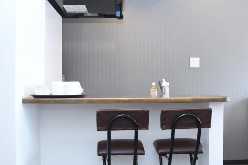 a bar with two stools at a counter at Hotel Urbansea 2 Matsuo in Naha