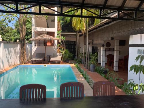 a swimming pool with chairs and a table and an umbrella at Private Boutique Home with Pool, The Fin Angkor Boutique in Siem Reap