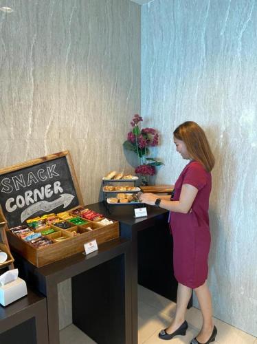 a woman standing in front of a table with food at News Hotel Waru Sidoarjo in Waru