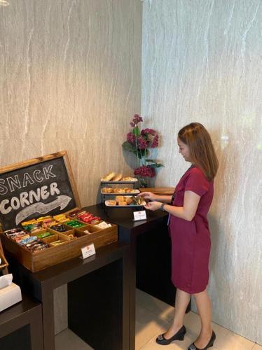 a woman standing in front of a table with food at News Hotel Waru Sidoarjo in Waru