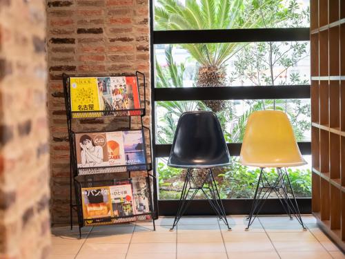 duas cadeiras e livros em frente a uma janela em ACCESS by LOISIR HOTEL Nagoya em Nagoya