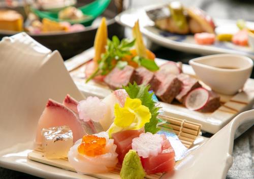 a plate of food with meats and vegetables on a table at Yufuin Onsen Hinoharu Ryokan in Yufu