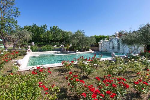 a swimming pool in a garden with red flowers at Sovana Hotel & Resort in Sovana