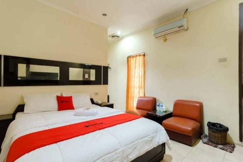 1 dormitorio con 1 cama grande y 1 silla en RedDoorz @ Dwipa Wisata Hotel, en Lampung
