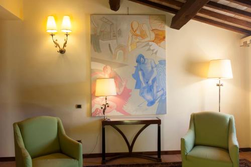 two chairs and a table in a room with a painting at Sovana Hotel & Resort in Sovana