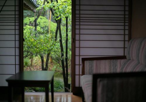 a door to a room with a table and a window at Yufuin Onsen Hinoharu Ryokan in Yufu