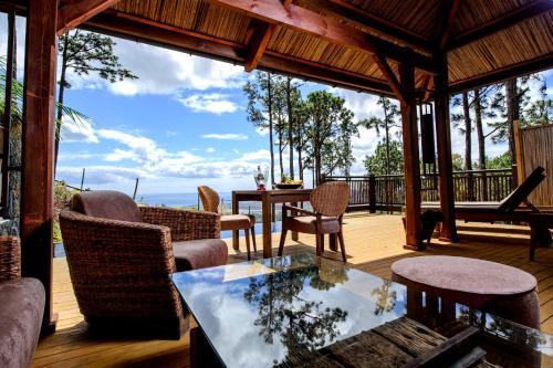 eine abgeschirmte Veranda mit einem Tisch und Stühlen in der Unterkunft Lakaz Chamarel Exclusive Lodge in Chamarel