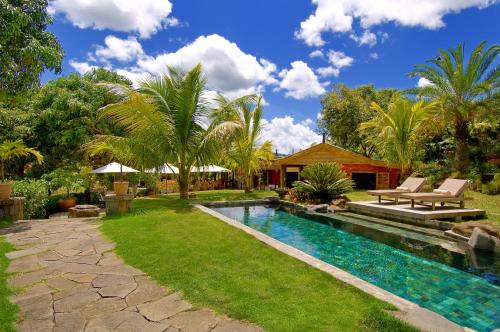 a backyard with a swimming pool and palm trees at Lakaz Chamarel Exclusive Lodge in Chamarel