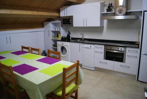 a kitchen with a table and a kitchen with white cabinets at Hostal Peñacárdena in Igea