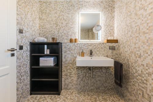 ein Bad mit einem Waschbecken und einem Spiegel in der Unterkunft Haus Therese mit Sauna in Zingst
