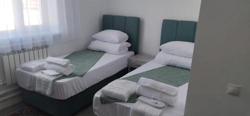 two twin beds in a small room with towels at Sulo Aksai Hotel in Aksay