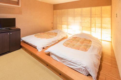 a bedroom with two beds and a television at Yushintei in Hakone