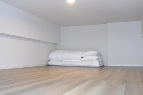 a bed in an empty room with a wooden floor at Hotel Tomas Asahibashi Station in Naha