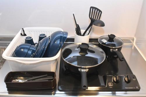 a tray with a pot and utensils on a stove at Hotel Tomas Asahibashi Station in Naha