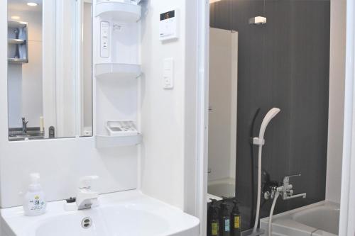 a white bathroom with a sink and a shower at Hotel Tomas Asahibashi Station in Naha
