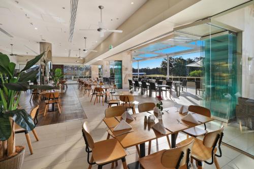 an empty restaurant with wooden tables and chairs at Pelican Waters Golf Resort Sunshine Coast in Caloundra
