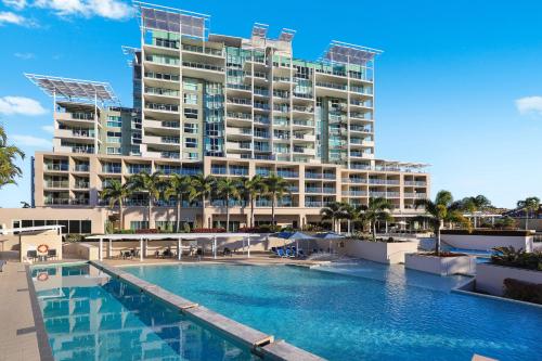a hotel with a swimming pool in front of a building at Pelican Waters Golf Resort Sunshine Coast in Caloundra