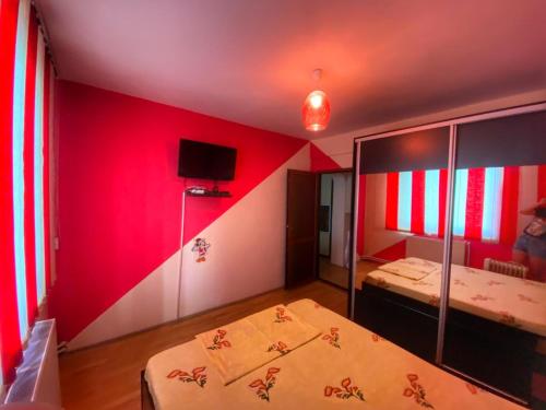 a room with two beds and a red wall at Apartament Sira in Sulina