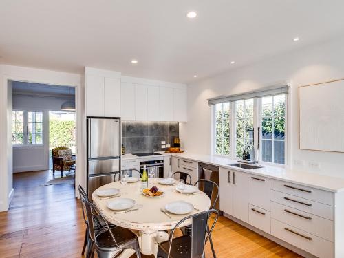 a white kitchen with a table and chairs in it at Gem on Gillean - Havelock North Holiday Home in Havelock North