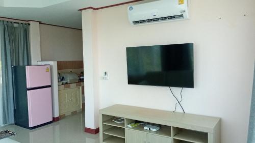 een woonkamer met een tv aan de muur en een koelkast bij บ้านชมวิว@แสมสาร in Ban Samae San