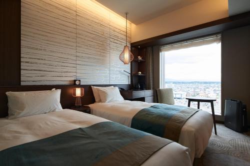 two beds in a hotel room with a window at Hotel Metropolitan Akita in Akita