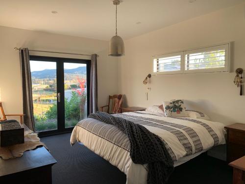 a bedroom with a bed and a large window at Millfield Garden Cottage in Millfield