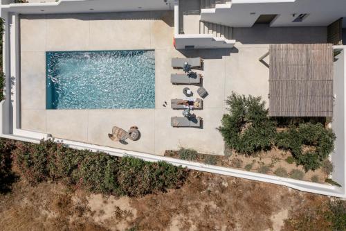 an overhead view of a swimming pool with chaise lounge chairs at Sea & Olives Suites Hotel and Villas in Plaka