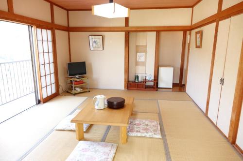 a living room with a table and a tv at ペンション桜家 in Shimoda