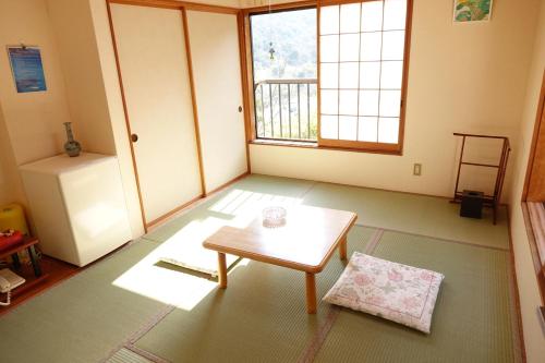 a living room with a coffee table and a window at ペンション桜家 in Shimoda