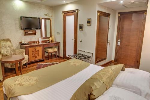 a bedroom with a bed and a desk and a television at Bulbul Yuvası Boutique Hotel in Foca