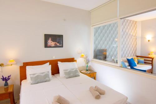 a bedroom with a large white bed and a window at Bellevue Suites in Agios Nikolaos
