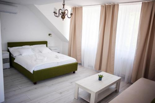 a bedroom with a green bed and a table at Q-Panzió in Tata